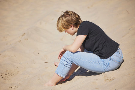 Teenage girl sitting on the beach in Denmarkの写真素材
