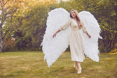 Beautiful girl dressed as an angel in the evening gardenの写真素材