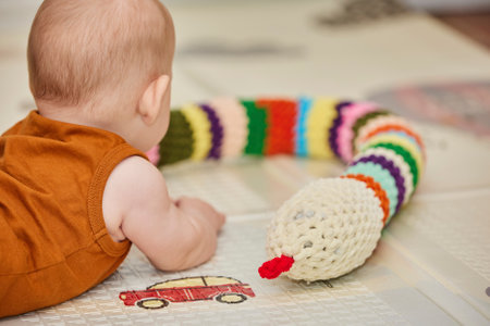 baby plays with a knitted toy in the nursery