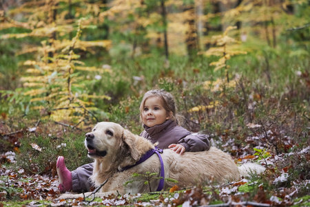 Charming child and dog walking in the forest in Denmarkの写真素材