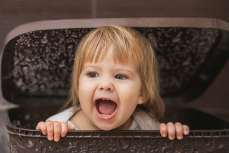 adorable baby hiding in a laundry basketの写真素材
