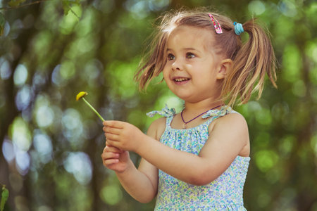Cute child tearing off flower petals while playing - loves or dislikeの写真素材