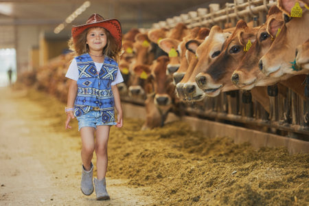Charming child in a cowboy costume on a cows farmの写真素材