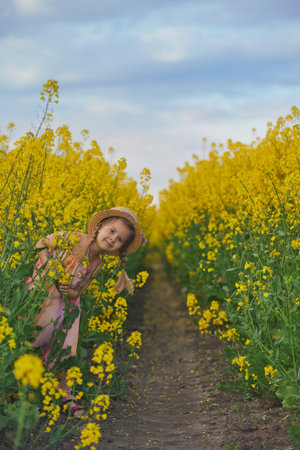 charming child in sundress in a rapeseed fieldの写真素材