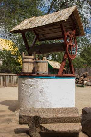 Two wooden buckets standing on the lid of a wellの写真素材