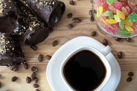 White cup of coffee with chocolate tubes, chocolate peanuts and multicolored sweet lollipops close upの写真素材