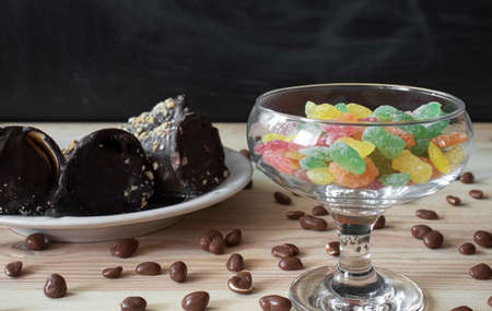 Chocolate tubes with filling, chocolate peanuts and colorful sweet lollipops on wooden table top close upの写真素材