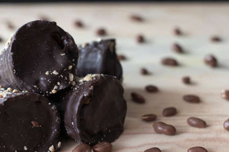 Chocolate tubes with filling and chocolate peanuts on wooden table top close upの写真素材