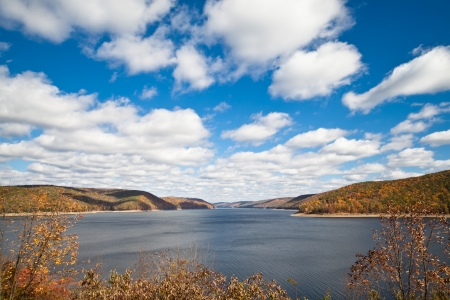 River surrounded by Autumn forest mountains under blue skyの写真素材
