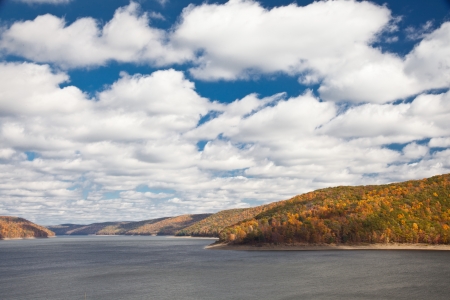 River surrounded by Autumn forest mountains under blue skyの写真素材