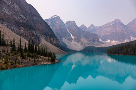Lake Moraine Turquoise Water Mirror Surface with Canadian Rocky Mountains Behind, Summer Day Haze, Banff National Park, Alberta, Canadaの写真素材