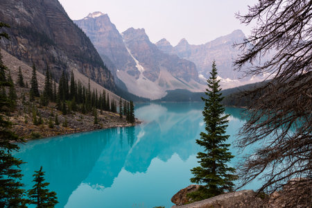 Lake Moraine Turquoise Water Mirror Surface with Canadian Rocky Mountains Behind, Summer Day Haze, Banff National Park, Alberta, Canadaの写真素材