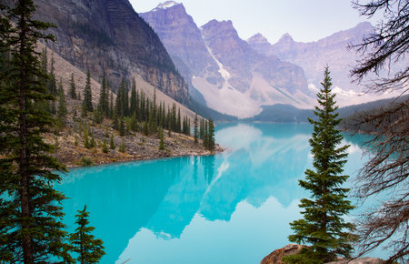 Lake Moraine Turquoise Water Mirror Surface with Canadian Rocky Mountains Behind, Summer Day Haze, Banff National Park, Alberta, Canadaの写真素材