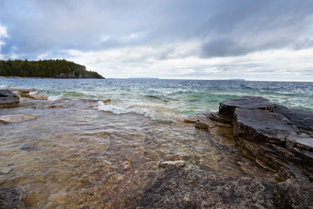 Dark Limestone Platforms in Turquoise waters of Lake Huron, shoreline coast beach near Cyprus Lake, stormy autumn dayの写真素材
