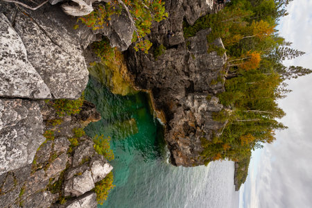 Rugged Rocky Limestone Coast Shoreline Cliffs Surrounded by Turquoise Water of Lake Huron. Stormy Autumn Day near Indian Head trail, Ontario, Canadaの写真素材