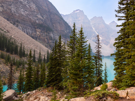 Lake Moraine Turquoise Water Mirror Surface with Canadian Rocky Mountains Behind, Summer Day Haze, Banff National Park, Alberta, Canadaの写真素材