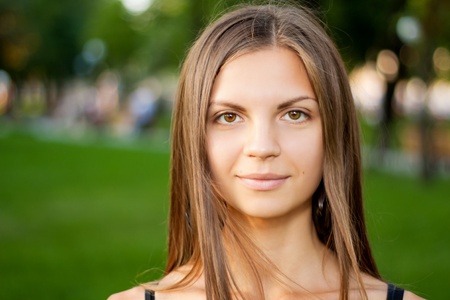 Portrait of a beautiful young smiling woman in green summer city parkの写真素材