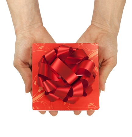 hands giving the gift with a red bow in the foregroundの写真素材