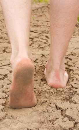 Man goes on the clay cracked earth. Legs closeup.の写真素材