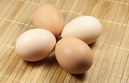 two beige and two brown eggs are on a striped rugの写真素材