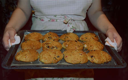 Homemade cookies. Thin female hands hold a hot baking tray with ready-made delicious pastries in...