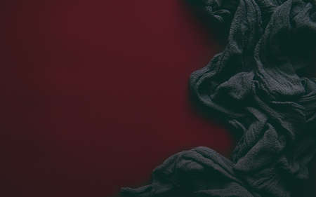 On a red background-a black textured fabric, symbolizing the struggle of humanity against evil. red as blood spilled during the struggle, black as evil.photo with a haze effect.Space for textの写真素材