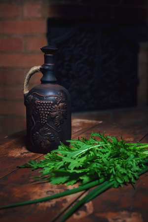 Traditional decorated with decorative ornaments Caucasian Georgian or Mediterranean Italian clay jug with red or white wine grapes. The photo is isolated on a dark background.の写真素材
