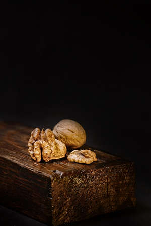 Half a split walnut on a black isolated background. Walnuts in a shell on a dark brown wooden...