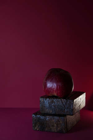 red apple on a dark red background with space for text. the concept of simplicity and grace. Advertising of exclusive products and services for the most demanding clients. The brand of the company.の写真素材