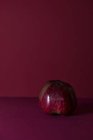 red apple on a dark red background with space for text. the concept of simplicity and grace. Advertising of exclusive products and services for the most demanding clients. The brand of the company.の写真素材