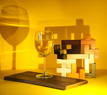 A glass of white wine, on a yellow background with an abstract pattern, the play of chiaroscuro emphasizes the exclusivity of the wine. non-standard approach in advertising. banner, alcoholic beveragesの写真素材