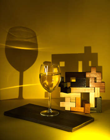 A glass of white wine, on a yellow background with an abstract pattern, the play of chiaroscuro emphasizes the exclusivity of the wine. non-standard approach in advertising. banner, alcoholic beveragesの写真素材