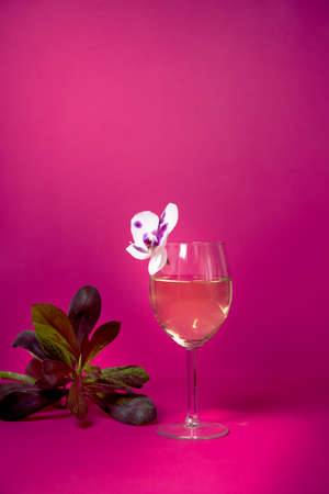 a glass of wine on a bright background with delicate orchids. ready for layout and layout. label for any name and variety. advertising of wines and restaurantsの写真素材