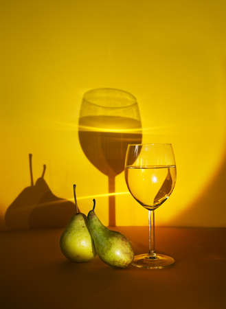 a glass of white wine on a yellow background. exclusive design and development of advertising of alcoholic beverages. the play of chiaroscuro increases the attention to alcoholic beverages.の写真素材