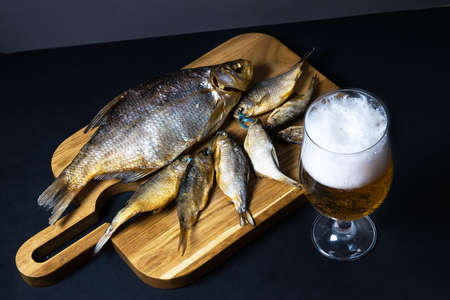 dried salted roach and bream, delicious clip fish on a wooden background with a glass of fresh beer. A popular beer snack. advertising of beer restaurants. Close-up, copy space. selective focus.bannerの写真素材