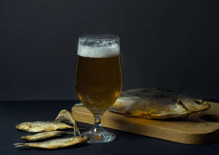 dried salted roach and bream, delicious clip fish on a wooden background with a glass of fresh beer....
