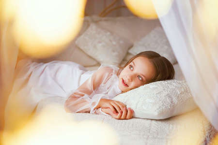 a very young lady remembers happy moments and dreams of new adventures.cozy children's room in a vintage style. atmospheric photo. the concept of a good mood and a happy childhood.の写真素材