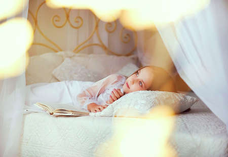 a little girl on her birthday dreams of a gift. in anticipation of the holiday and fun. a happy childhood, a pleasant and carefree time. the concept of comfort and home warmth. stylish children's roomの写真素材