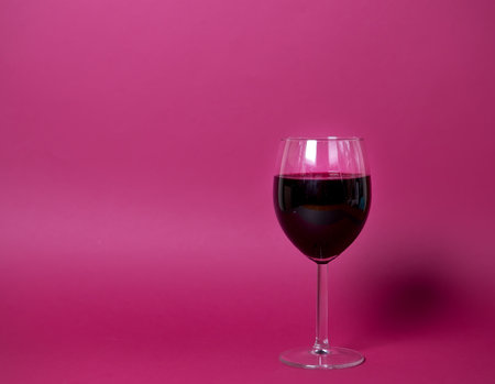 a glass of red wine on a bright pink background close-up, isolated object. suitable for advertising wine restaurant, wine list of wine factory products. copy spaceの写真素材