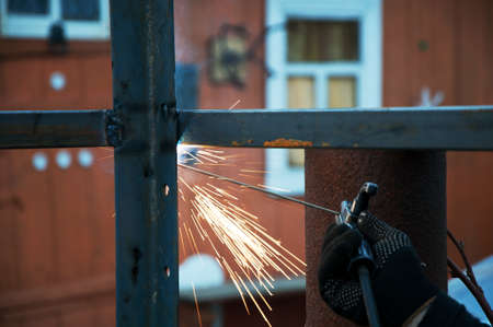 Welding work on the street. The welder will produce metal parts on the site. welding of the metal frame, the work takes place on the street, the metal welding process is visible in close-up.の写真素材