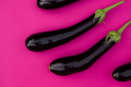 ripe eggplants on a bright crimson background. a poster for the dining room, an advertisement for farm products, a stylish picture for the interior of the store.の写真素材