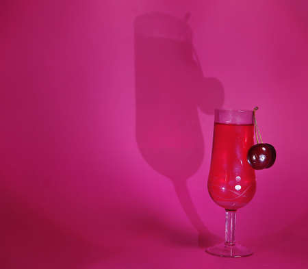 cherries and a glass of red wine in the background.Close-up with space for copying.stylish photography, the play of chiaroscuro stops the eye and attracts attention. for the presentation of new drinksの写真素材
