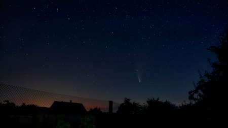 Beautiful view of the starry sky and comet C.2020 F3 NEOWISE with a light tail. a fascinating view from the window of your house outside the city.の写真素材