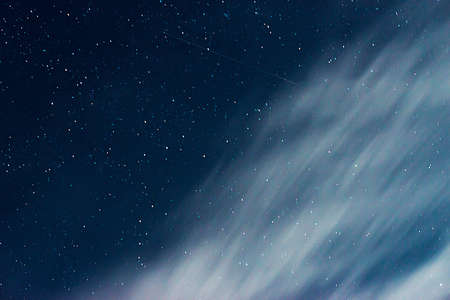 against the background of the starry sky. shooting stars fly between the clouds and outer space, connecting the mundane and the galaxy. nebula and defocusing of the composition. the hazy galaxy effectの写真素材