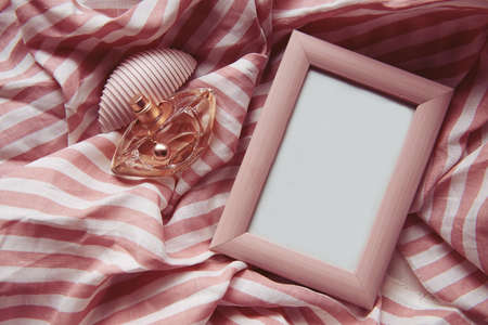 a perfume bottle on a pink airy background with a pink frame. retro-filtered image .High viewing angle of perfume bottle and abstract photo frame on pink background.の写真素材