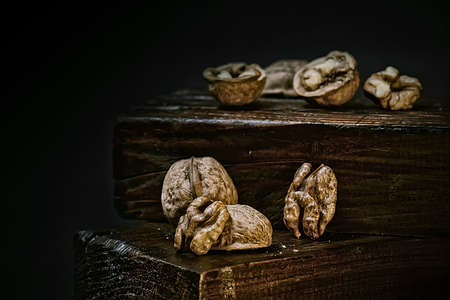Half a split walnut on a black isolated background. Walnuts in a shell on a dark brown wooden background. Rustic background. selective focus.の写真素材