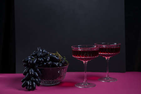 2 wine glasses, a bottle of red wine, a bunch of dark grapes. a stylish, tempting offer advertising red wine. space for copying. wine list. restaurant advertising.romantic dinner for two.の写真素材