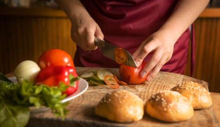 Close-up of a woman cutting vegetables with a sharp kitchen knife. Cooking healthy organic food in the home kitchen. The concept of a natural clean diet and a healthy lifestyle. selective focusの写真素材
