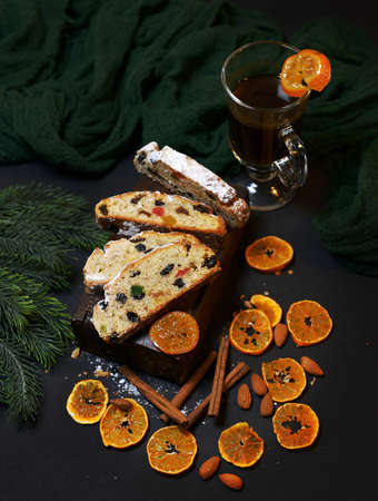 Traditional Christmas cake decorated with frosting, candied fruits, tangerines and cinnamon, place for text. Banner design. selective focus, photography in low key. aromas of the new year.の写真素材
