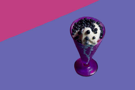 An amazing dessert of ice cream and blueberries in a purple vase with fresh blueberries on a bright background. isolated object. copy space, advertising - suitable for any field of activity. Very periの写真素材